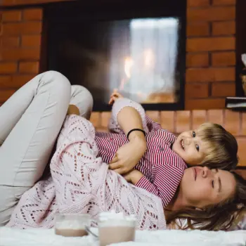 Mère et son enfant devant une cheminée.