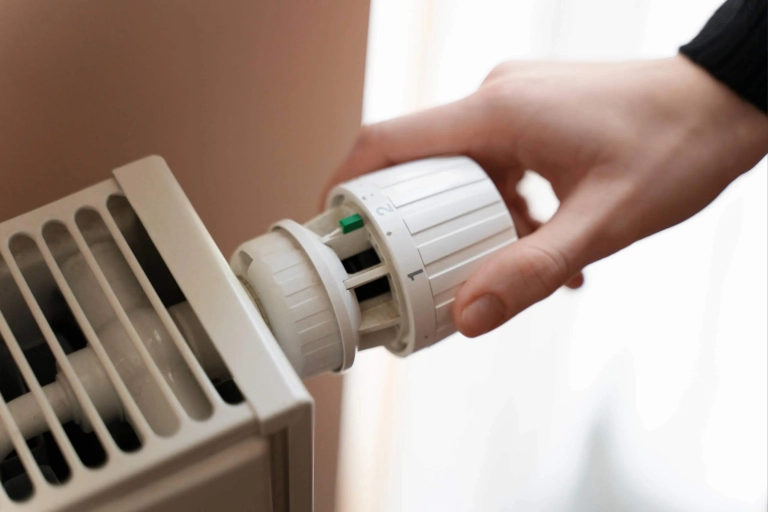 Personne réglant la température sur un radiateur